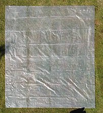 Aufbau der Hüpfburg mit Schutzplane auf dem Rasen